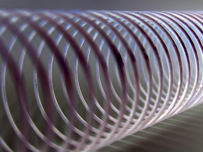Free Stock Photo: Extreme close up of coiled metal spring with purple tones against a light background