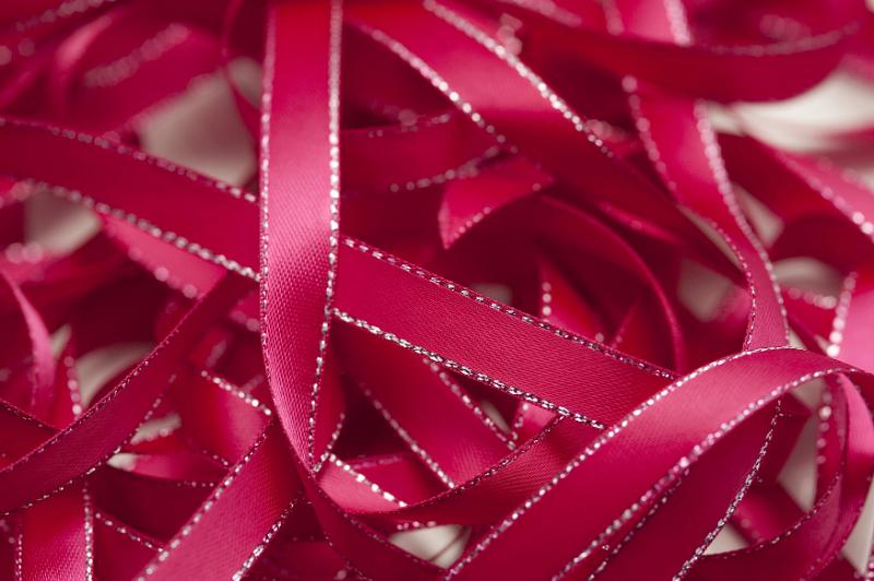 Free Stock Photo: Close up of unraveled pink ribbon with silver trim against white background