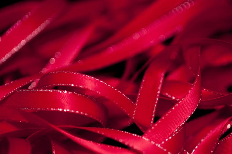 Free Stock Photo: Unraveled red satin ribbon with shiny trim against a black background