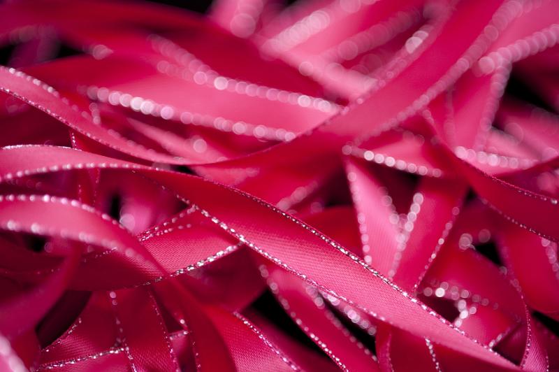 Free Stock Photo: Close up of unwound deep pink satin ribbon with silver trim against a black background
