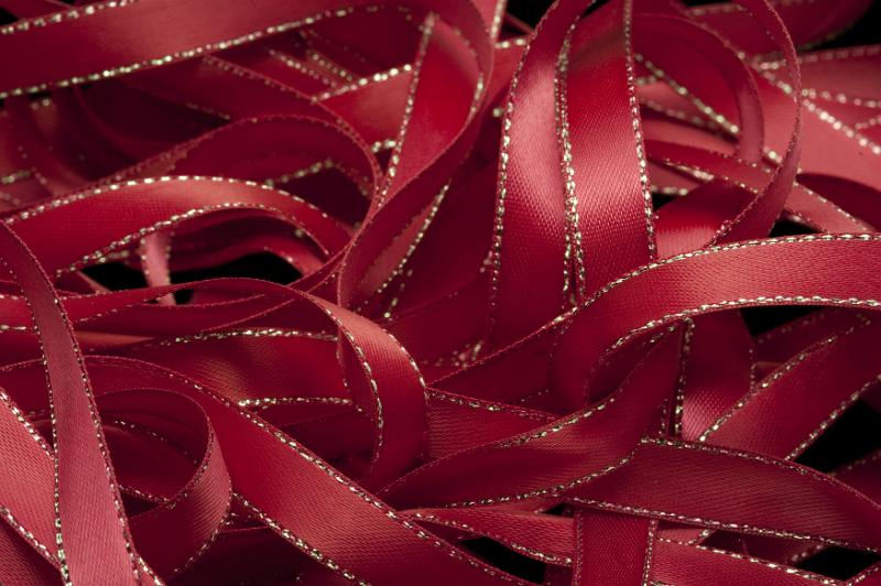 Free Stock Photo: Cropped close up on pile of dark red gift ribbons with gold trim as full frame background with copy space