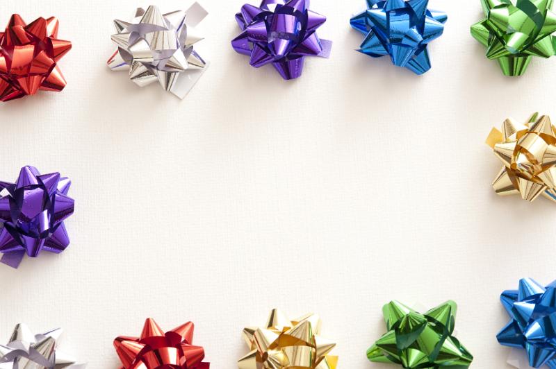 Free Stock Photo: Border of colorful shiny metallic ribbon bows for packaging gifts around a central white copy space for a festive celebration