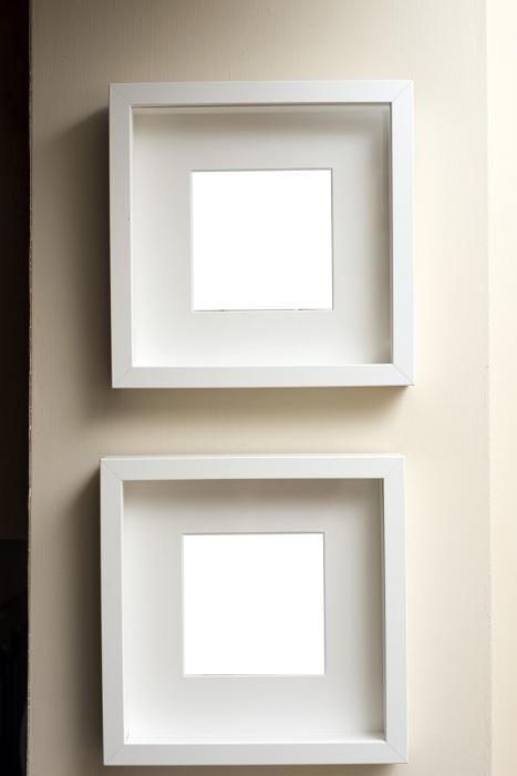 Free Stock Photo: Two empty square neutral colored frames hanging together on an off white wall one below the other