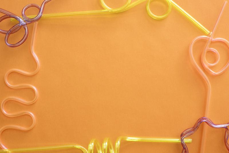 Free Stock Photo: Bendy straw decorative party frame with colorful straws bent into assorted shapes and patterns on an orange background with copy space