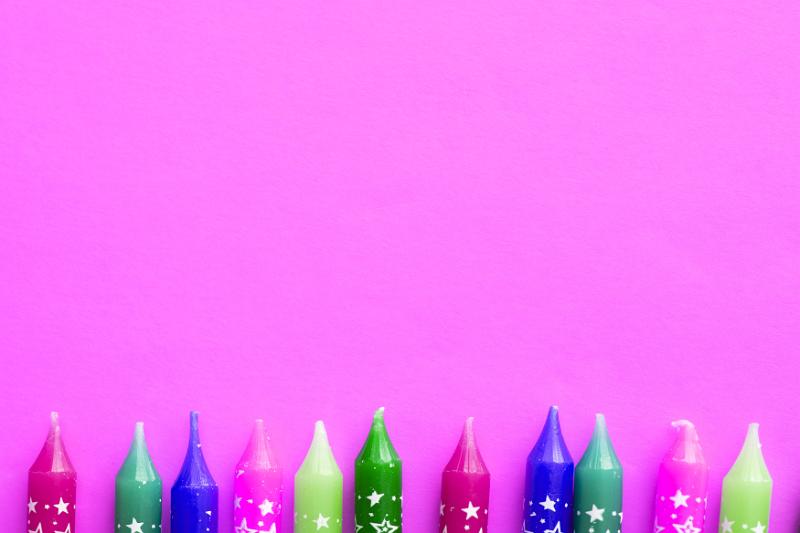 Free Stock Photo: Colorful girls birthday border with the tips of new unused party candles decorated with stars on a bright pink background with copy space for your greeting