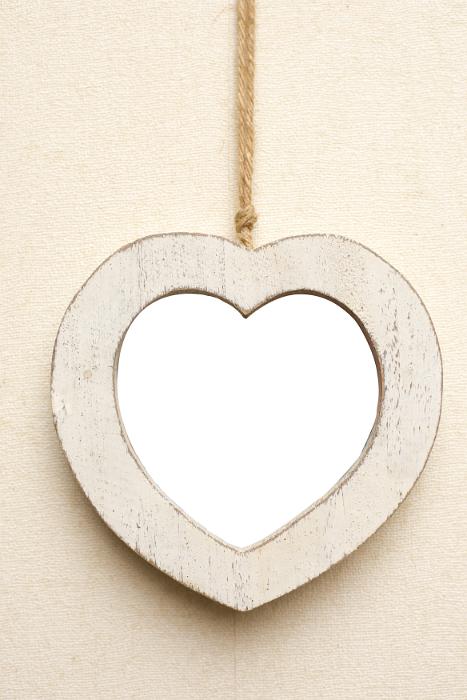 Free Stock Photo: Rustic off white wooden heart shaped picture frame hanging by a cord on a cream colored background with central copy space for your love or romance themed artwork