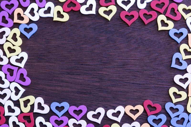Free Stock Photo: Colorful heart frame with decorative cut out heart shapes on wood with central copy space for your romantic message of love
