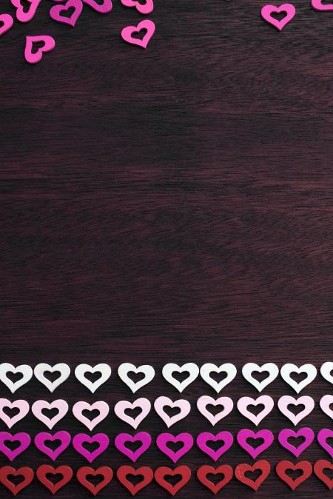 Free Stock Photo: Colorful border of rows of red, white, pink and magenta hearts on dark wood with space for your romantic or love themed message
