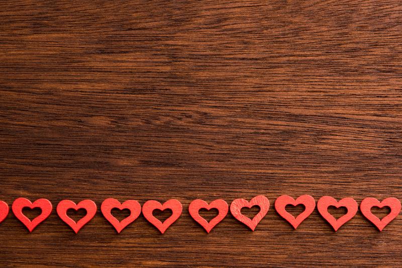 Free Stock Photo: Line of foam heart shapes near bottom of dark wooden panel as background with copy space