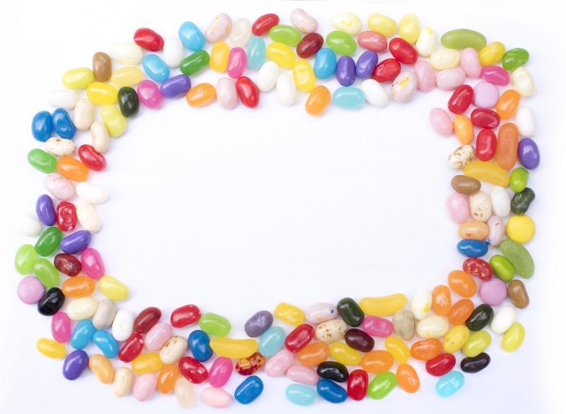 Free Stock Photo: Colorful jujube or jelly bean frame with brightly colored candy in the colors of the rainbow on white with central copy space