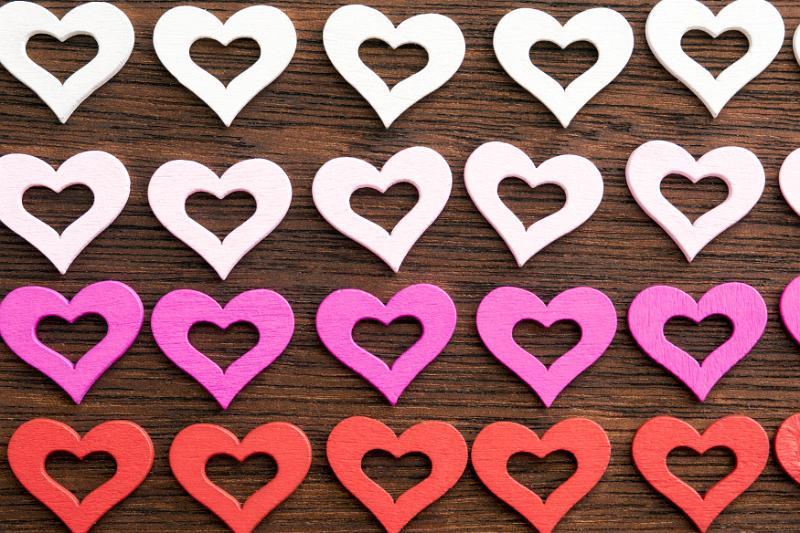 Free Stock Photo: Wooden hearts background with modern cut outs arranged in four rows graduating from white through pink to red on wood symbolic of love and romance