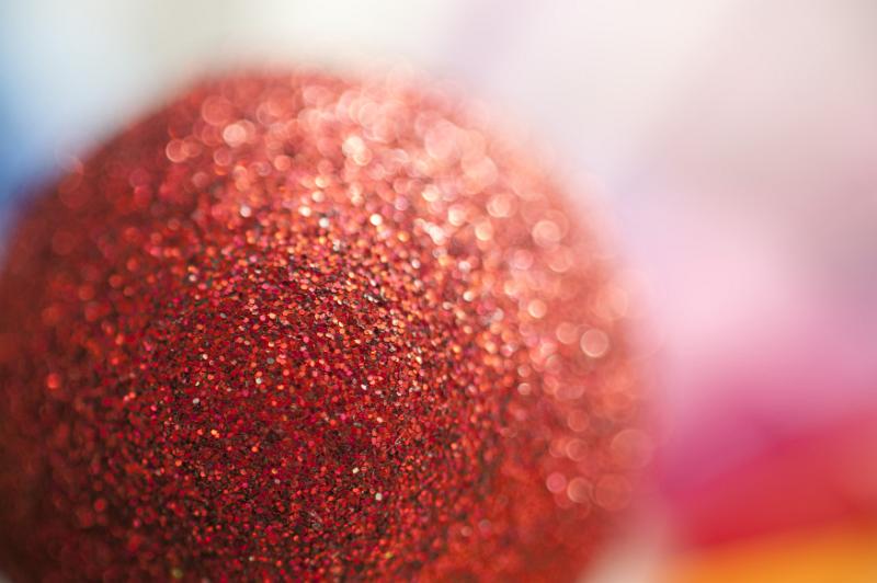 Free Stock Photo: Close Up of Red Glitter Christmas Ornament Ball in Diffuse Focus with Colorful Background and Copy Space