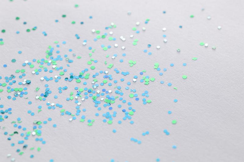 Free Stock Photo: Scattered pieces of blue and green glitter sprinkled on gray paper as background