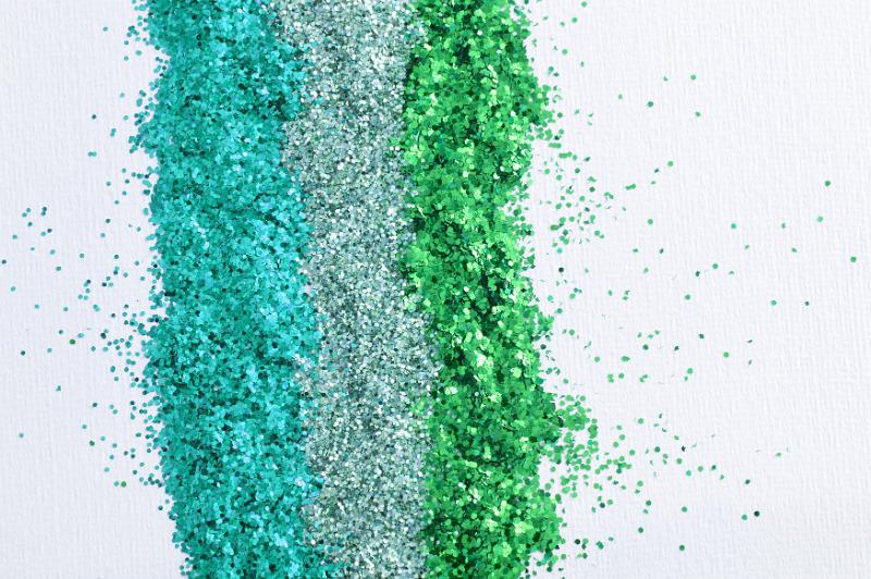 Free Stock Photo: Colorful green craft glitter in three different shades in parallel lines on white with copy space, overhead view