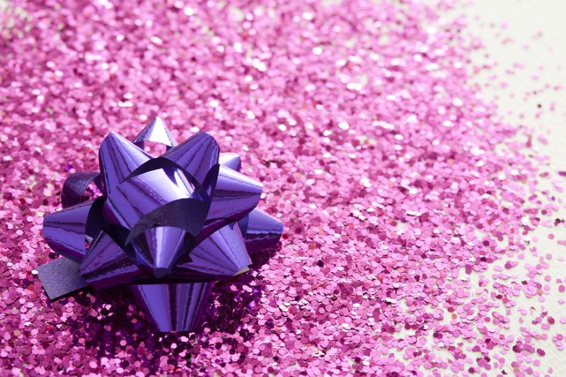 Free Stock Photo: Celebratory Full Frame Background of Sparkling Pink Glitter and Shiny Metallic Purple Gift Bow in Bright Studio with Selective Focus and Copy Space