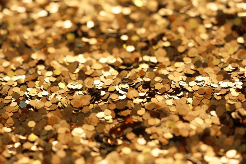 Free Stock Photo: A background of golden glitter sprinkles pictured in narrow depth of field with copy space in the foreground and rear