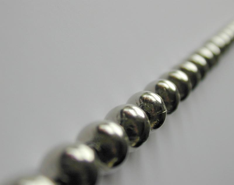Free Stock Photo: Extreme close up view of metal beads strung together into a chain against a grey background
