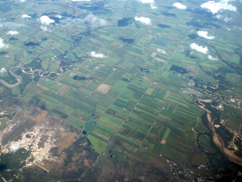 Free Stock Photo: High angle airplane view of cultivated land and waterways with clouds above and reflective swamp