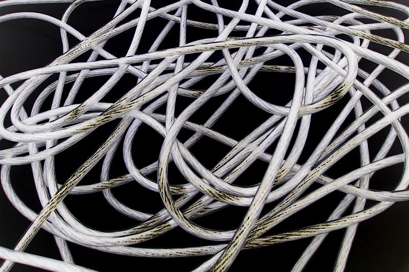 Free Stock Photo: Full frame top down view on tangled white rope encased with plastic and partially covered in oil smudges over black background