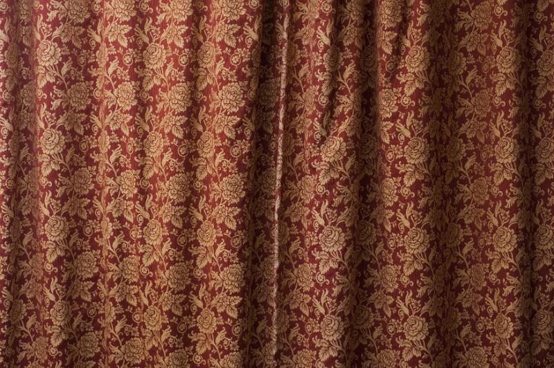 Free Stock Photo: Closed drapes of red and gold brocade curtaining decorated with flowers in a full frame texture background