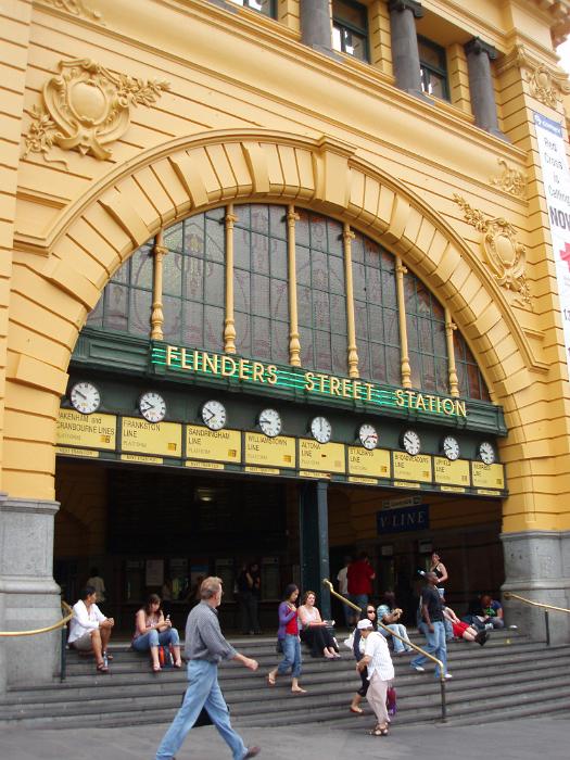 Free Stock Photo: Ornate arched entrance to Flinders Street Station, Melbourne, Australia, with people sitting on the steps and commuters making their way to and from the trains