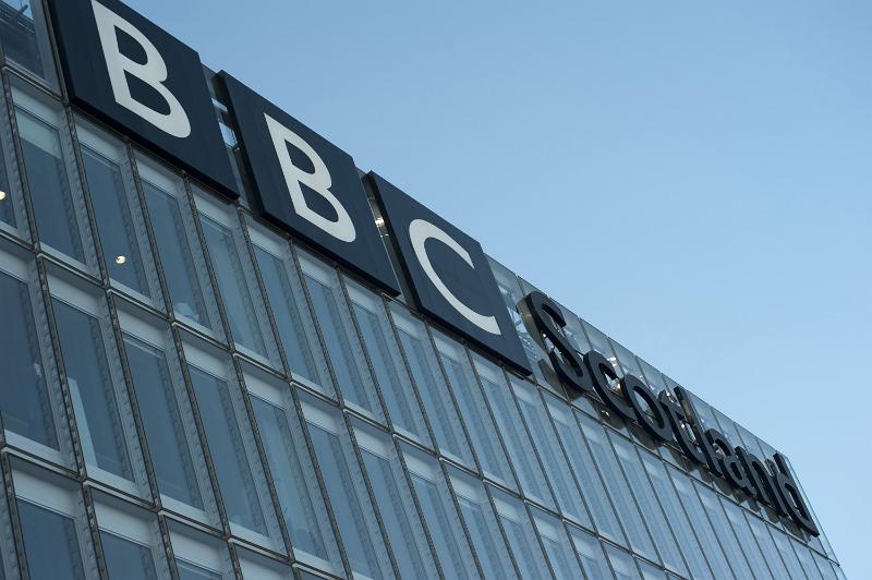 Free Stock Photo: BBC Scotland building facade showing the signage at the top of the building, oblique angle from below against a blue sky