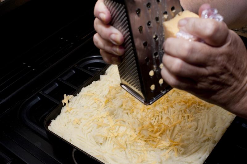 Free Stock Photo: Grating cheese over the mashed potato topping on a cottage pie before place it in the oven to bake or grill