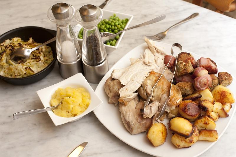 Free Stock Photo: Chicken roast carved and displayed on a plate with golden roast potatoes and individual side servings of vegetables