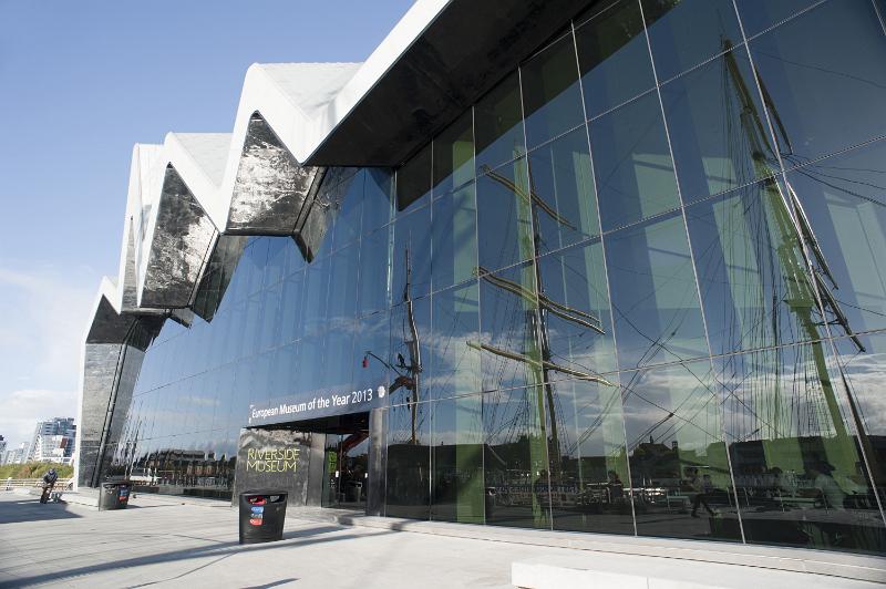 Free Stock Photo: Entrance to the Riverside Museum in Glasgow with its modern zigzag glass facade reflecting a tall ship exhibit in the harbour