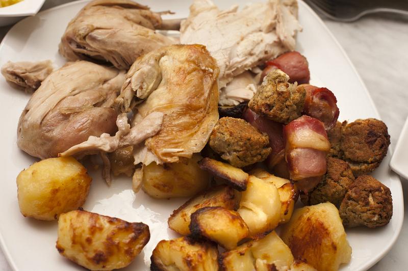 Free Stock Photo: Roast dinner ready for serving on a plate with carved chicken or turkey accompanied by golden roast potatoes, close up view