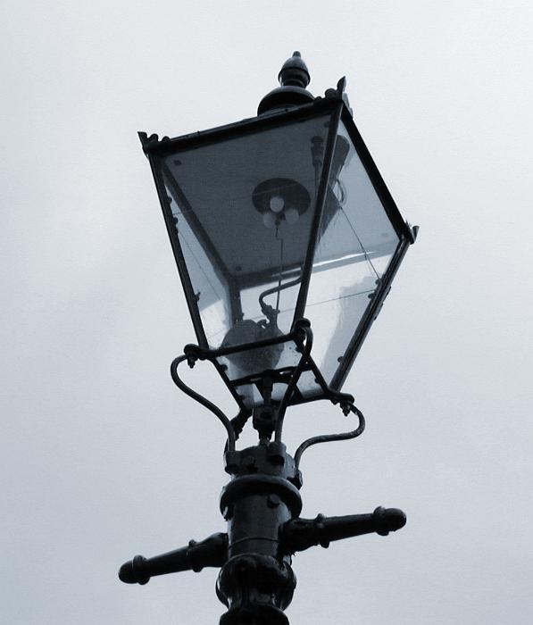 Free Stock Photo: Old Victorian gas streetlamp with its wrought iron lantern against a dull grey sky, close up detail