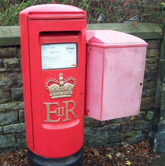 Free Stock Photo: Traditional red Royal Mail post box on a street alongside a stone wall in Great Britain
