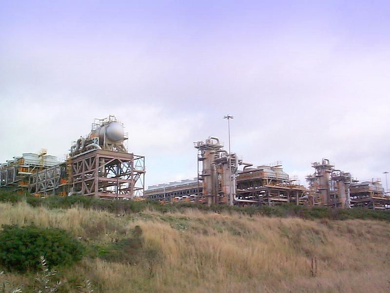 Free Stock Photo: Outdoor factory facilities with tanks and metal trusses constructions viewed from distance and from low angle, with withered grass and bushes in foreground