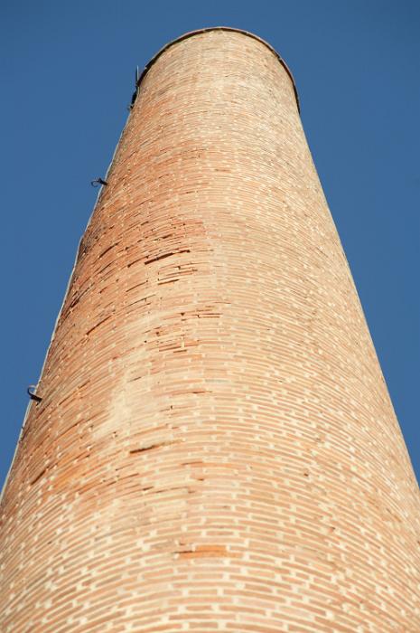 Free Stock Photo: Old cylindrical red brick industrial chimney or smokestack at a factory looking up from below to blue sky