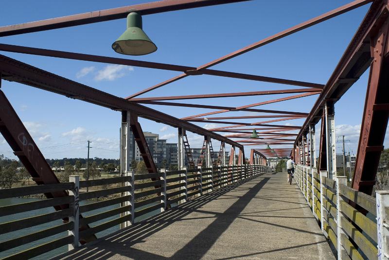 Free Stock Photo: View along a pedestrian and cycle crossing on an old steel bridge with open framework under a blue sky