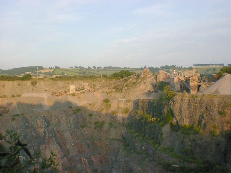 Free Stock Photo: Artificial landscape of a big old quarry with green plants growing on the steep slopes and factory facilities on top, viewed from across
