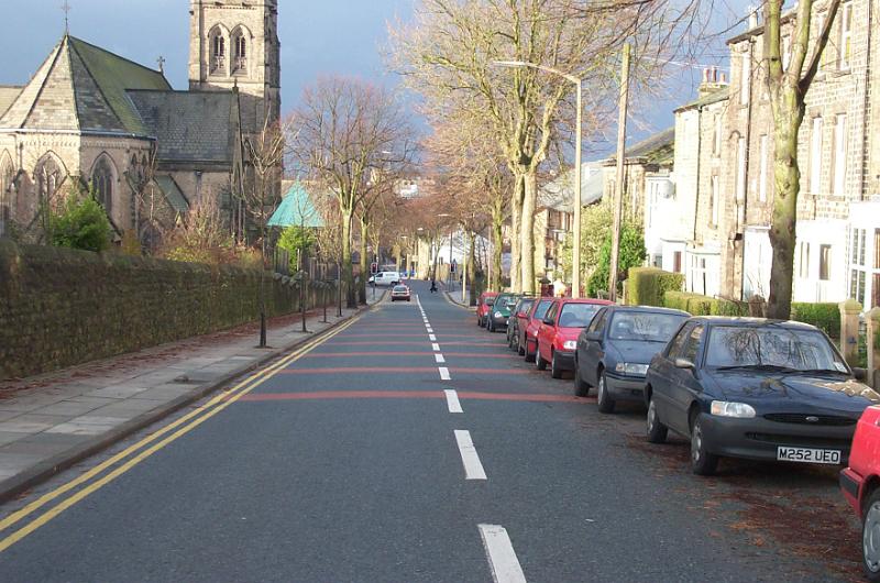 Free Stock Photo: Urban street with parked cars in front of residential apartments and old stone church bathed in evening light