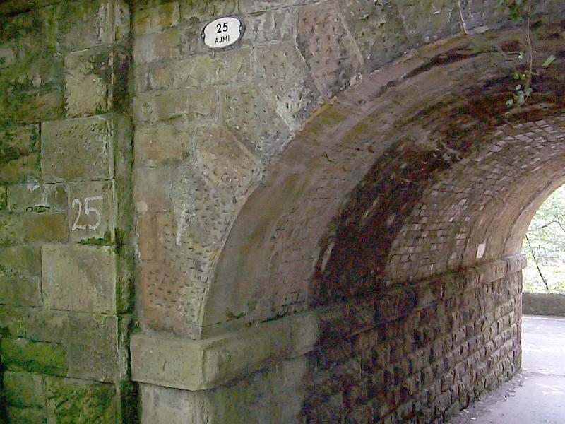 Free Stock Photo: Side of a stone arch of an old bridge with street number 25 attached to the wall