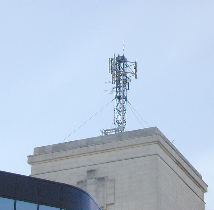 Free Stock Photo: Transmitter aerial on top of a flat roofed building viewed from below in a communications concept