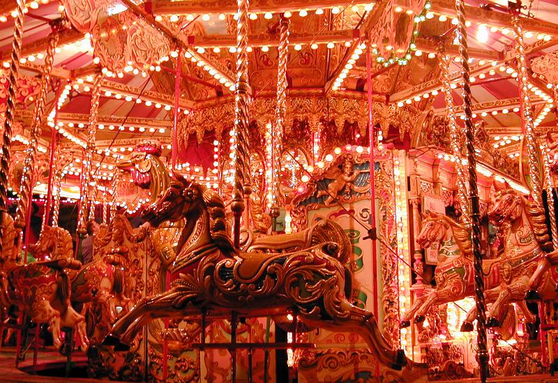 Free Stock Photo: Close up of an illuminated carousel at a funfair or amusement park with decorative horse rides