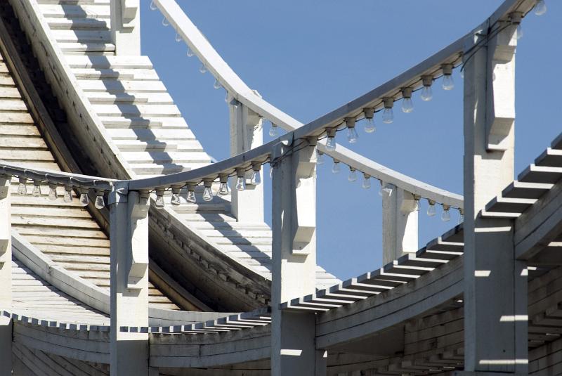 Free Stock Photo: A close up of a white roller coaster track and railing with a blue sky background.