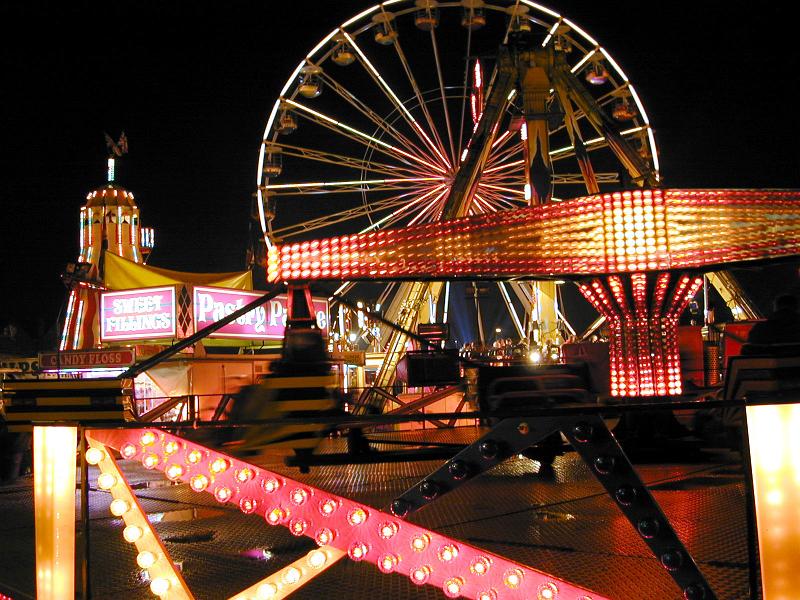 Free Stock Photo: Colorful illuminated amusement park at night with a view to a large ferris wheel in the background against a dark sky