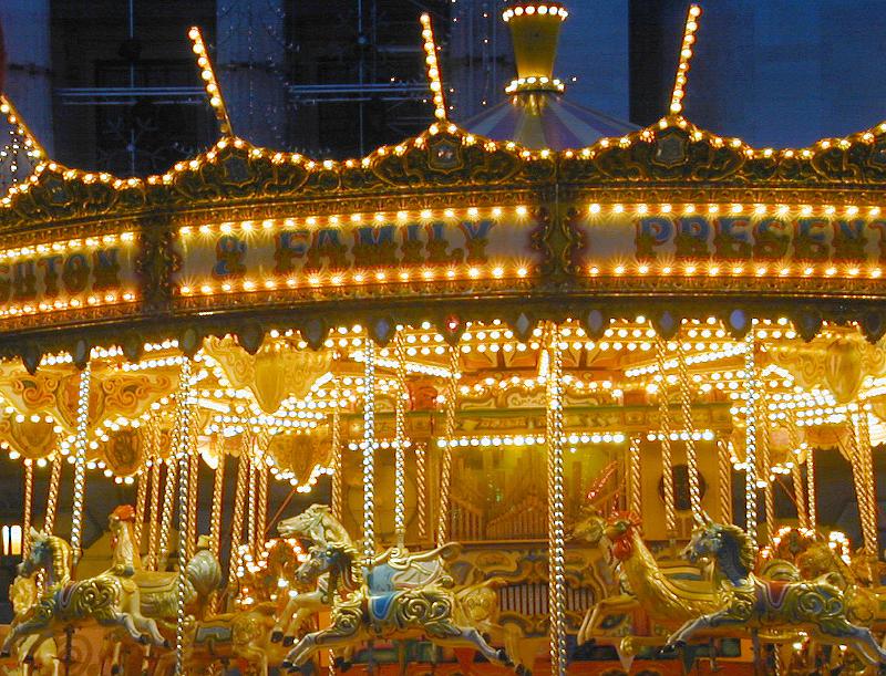 Free Stock Photo: Illuminated colorful festive carousel at night at a funfair or amusement park with horses to ride in a close up view