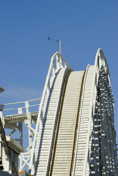 Free Stock Photo: Empty track of a rollercoaster at an amusement park cresting a hill against a clear blue sky in an entertainment concept and thrill seeking