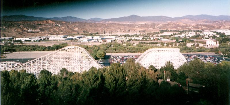 Free Stock Photo: Panoramic view of a Big Dipper rollercoaster at a them park or amusement park nestling amongst trees with town in the background