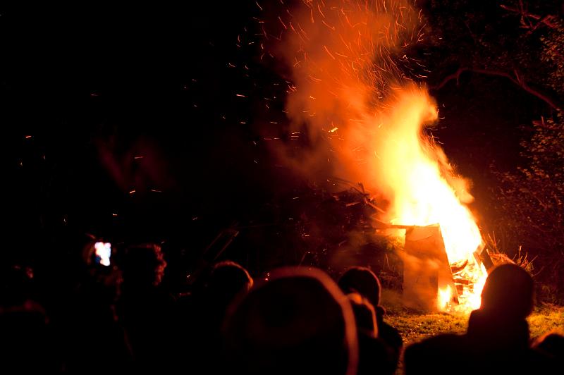 Free Stock Photo: Crowds of people celebrating Bonfire Night gathered in the darkness around a roaring bonfire with leaping orange flames