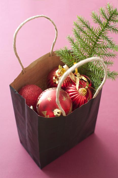 Download image of Bag full of colorful Christmas decorations Free Stock Photo: Bag full of colorful Christmas decorations with red baubles and pine branch over a red background