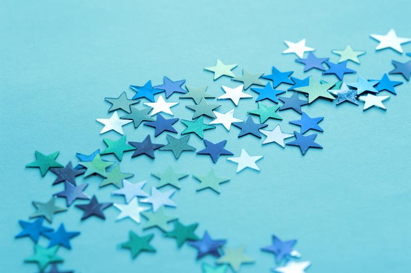 Free Stock Photo: Still Life of Blue and Silver Stars Scattered Across Teal Colored Background with Copy Space