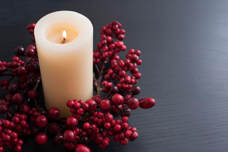 Download image of lit christmas candle Free Stock Photo: a lit church candle with a wreath of red berries on a plain background