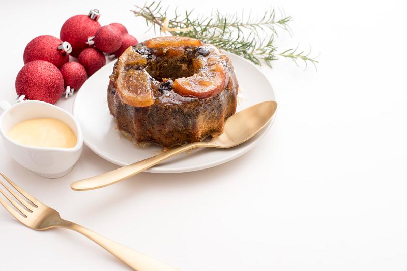 Free Stock Photo: christmas plum pudding with custard or brandy sauce on a plate with cuttlery